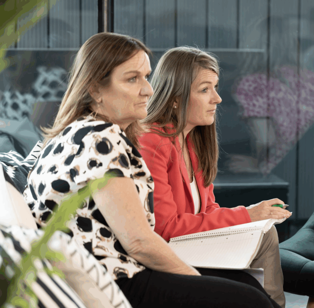 two-woman-sitting-down-in-office-setting